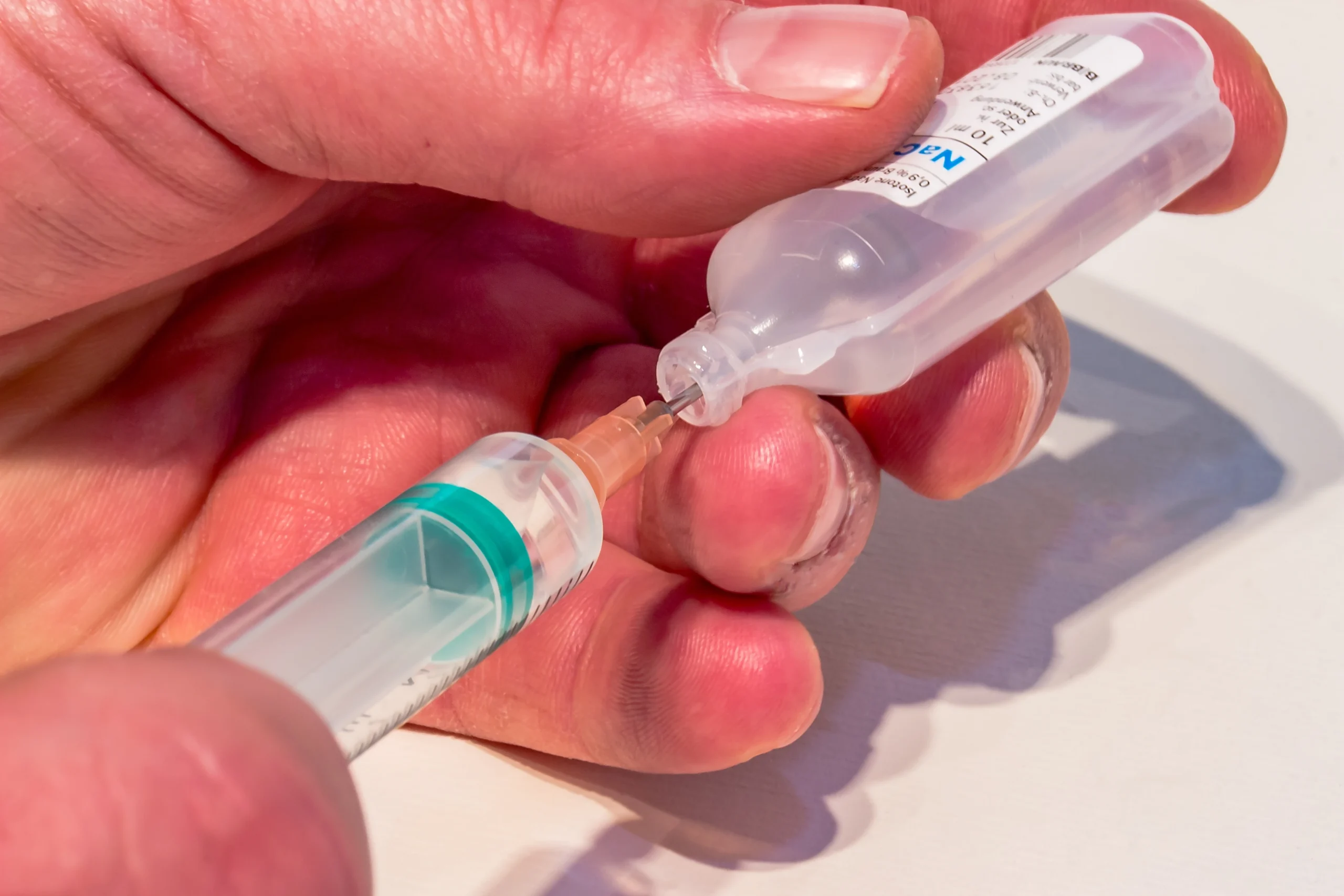 A person filling a vaccine syringe