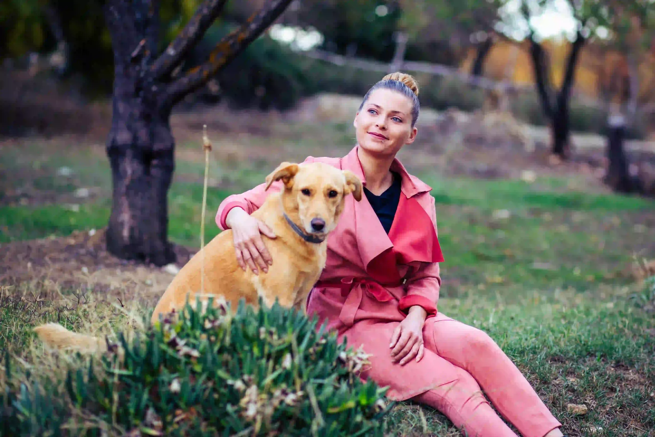 A woman sitting in the park with her dog